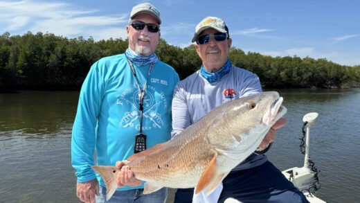 Captain Sergio and a guest holding a large speckled trout on a boat in Crystal River.